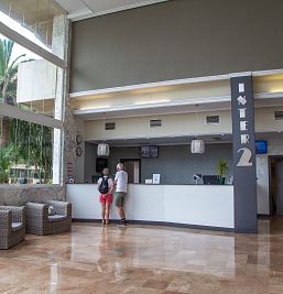 Recepción moderna y acogedora en Inter2 Salou, con personal atento para recibir a los huéspedes.